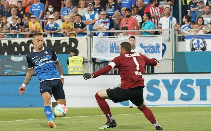 Phillip Tietz (l) schiebt nach dem Patzer von Hansa-Keeper Markus Kolke zum 1:0 für Darmstadt ein.