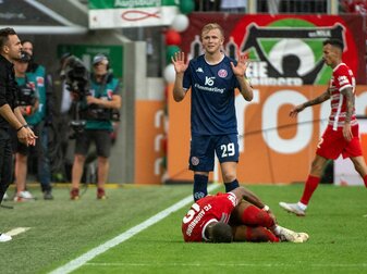 Augsburgs Felix Uduokhai (vorn) liegt beim Spiel gegen Mainz verletzt auf dem Rasen. Augsburgs Felix Uduokhai (vorn) liegt beim Spiel gegen Mainz verletzt auf dem Rasen.