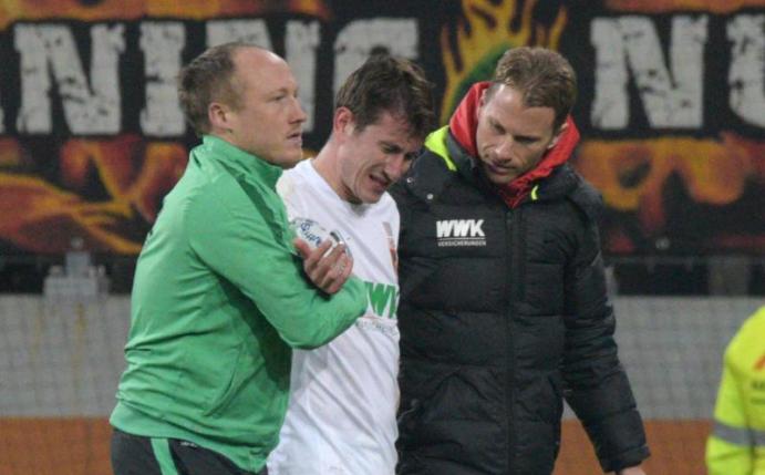 Paul Verhaegh (M) wird von Mannschaftsarzt Peter Stiller (l) vom Platz geführt. Foto: Stefan Puchner