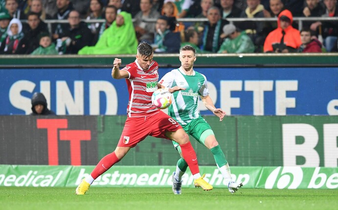 Augsburgs Ermedin Demirovic kämpft gegen Mitchell Weiser (r) von Werder Bremen um den Ball.
