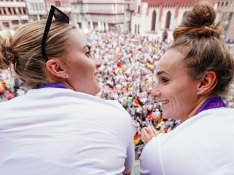 Die Spielerinnen Laura Freigang (l) und Lina Magull lassen sich auf dem Balkon des Römer von den Fans feiern. Die Spielerinnen Laura Freigang (l) und Lina Magull lassen sich auf dem Balkon des Römer von den Fans feiern.
