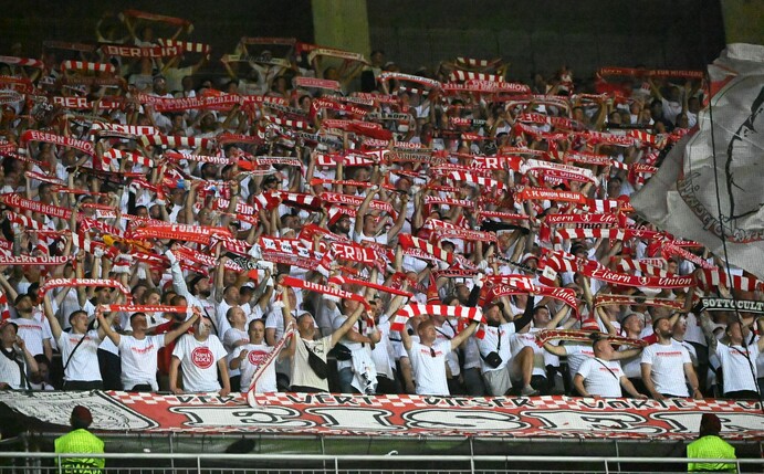 Die Fans von Union Berlin halten ihre Schals hoch.