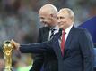 Die letzte WM 2018 richtete als Gastgeber Russland aus. Wladimir Putin steht neben FIFA-Präsident Gianni Infantino am WM-Pokal.