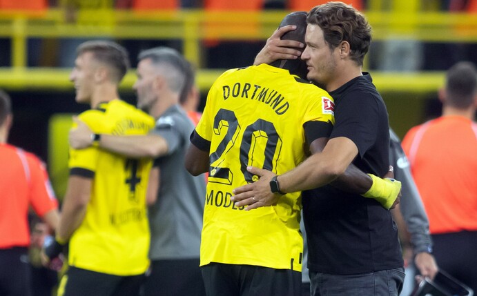 Dortmunds Trainer Edin Terzic (r) umarmt Anthony Modeste. Hinten Marco Reus.