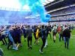 Fans von Manchester City stürmen das Spielfeld und jubeln über den Gewinn der englischen Meisterschaft.