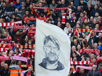 Liverpool-Fans präsentieren zur Unterstützung ihre Schals und halten ein Transparent mit einem Porträt von Trainer Jürgen Klopp. Liverpool-Fans präsentieren zur Unterstützung ihre Schals und halten ein Transparent mit einem Porträt von Trainer Jürgen Klopp.