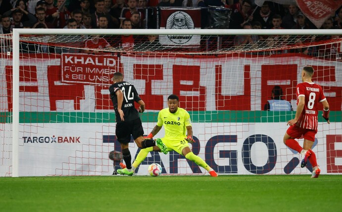 Freiburgs Torwart Noah Atubolu (M.) rettet gegen St. Paulis Etienne Amenyido.