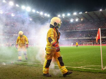 Feuerwehrleute löschen Bengalische Feuer während des Fußballspiels. Feuerwehrleute löschen Bengalische Feuer während des Fußballspiels.