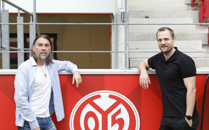 Mainz-Trainer Bo Svensson (r) steht neben Sportdirektor Martin Schmidt neben einem Logo des Vereins.