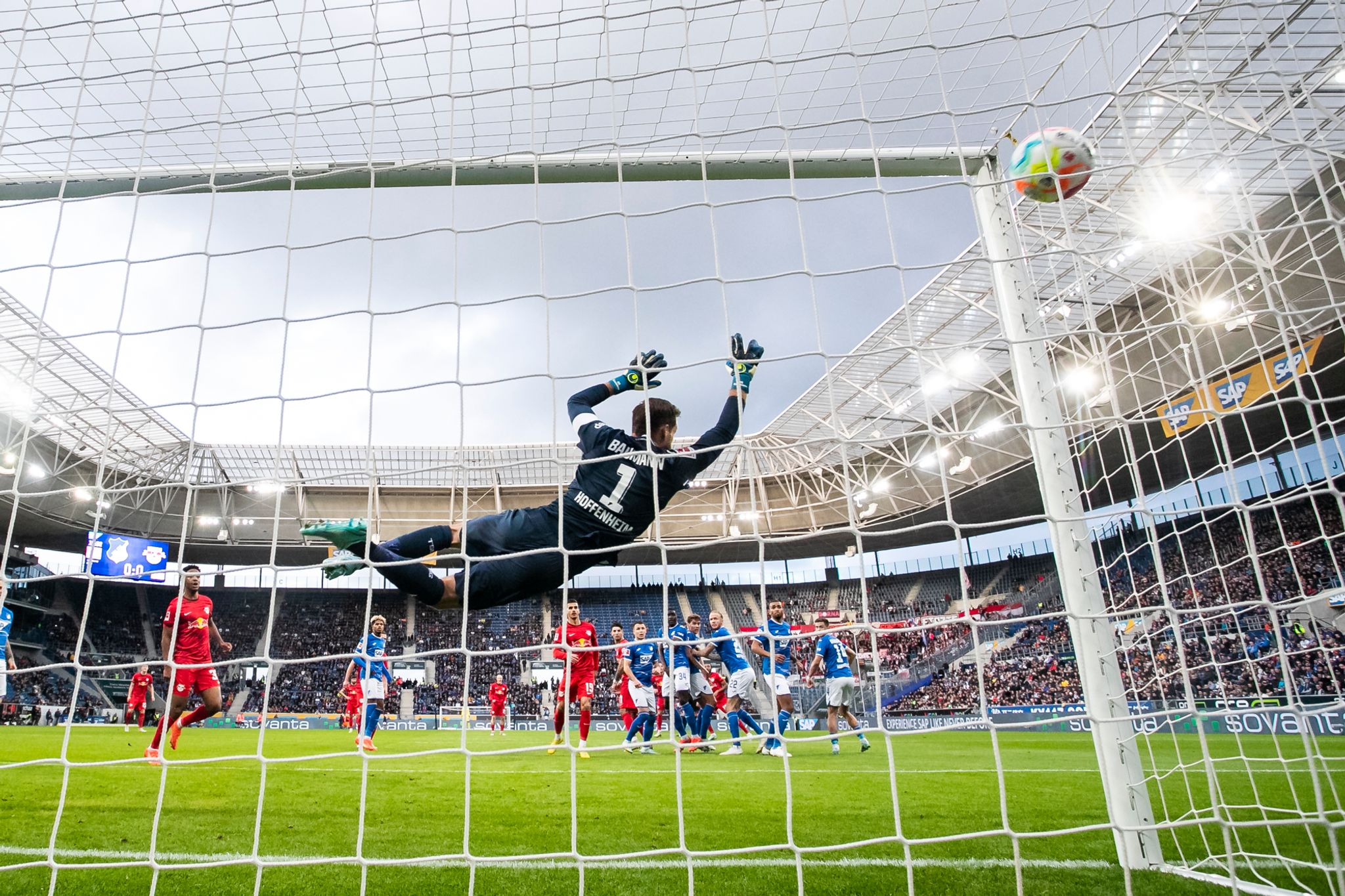 Leipzigs Christopher Nkunku (verdeckt) macht das Tor zum 0:1 gegen Hoffenheims Torwart Oliver Baumann (l).