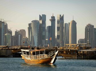 Dhow-Boote, wie sie früher die Perlentaucher genutzt haben, fahren mit Touristen im Meer vor der Skyline von Doha. Dhow-Boote, wie sie früher die Perlentaucher genutzt haben, fahren mit Touristen im Meer vor der Skyline von Doha.