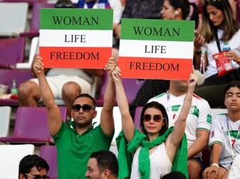 Iranische Fans auf der Tribüne halten vor dem Spiel Schilder mit der Aufschrift "Woman Life Freedom" hoch.