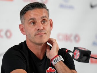 Kanadas Trainer John Herdman sitzt während einer Pressekonferenz auf dem Podium. Kanadas Trainer John Herdman sitzt während einer Pressekonferenz auf dem Podium.
