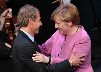 Der ehemalige Bundestrainer Jürgen Klinsmann und die frühere Bundeskanzlerin Angela Merkel (CDU) umarmen sich bei einem Festakt im Jahr 2016. Der ehemalige Bundestrainer Jürgen Klinsmann und die frühere Bundeskanzlerin Angela Merkel (CDU) umarmen sich bei einem Festakt im Jahr 2016.