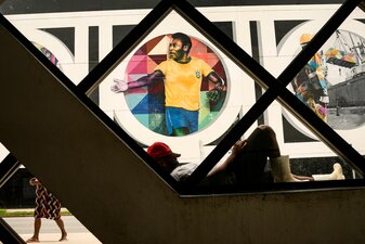 Ein Mann ruht sich vor einem Wandgemälde mit dem Bild der Fußballlegende Pele aus. Ein Mann ruht sich vor einem Wandgemälde mit dem Bild der Fußballlegende Pele aus.