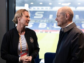 Bundeskanzler Olaf Scholz (SPD, r) spricht am Rande eines Spiels mit Martina Voss-Tecklenburg, Trainerin der deutschen Frauennationalmannschaft. Bundeskanzler Olaf Scholz (SPD, r) spricht am Rande eines Spiels mit Martina Voss-Tecklenburg, Trainerin der deutschen Frauennationalmannschaft.