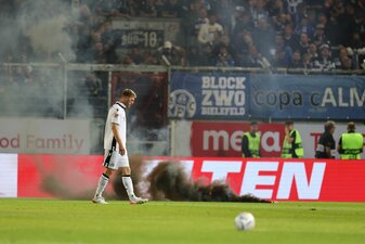 Bielefelds Fabian Klos läuft vor Rauchbomben auf dem Rasen. Bielefelds Fabian Klos läuft vor Rauchbomben auf dem Rasen.