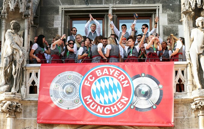 Spielerinnen und Spieler von Bayern München jubeln auf dem Rathaus-Balkon.