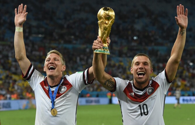 Bastian Schweinsteiger (l) und Lukas Podolski jubeln nach dem Sieg der FIFA-Weltmeisterschaft 2014 mit dem Pokal.