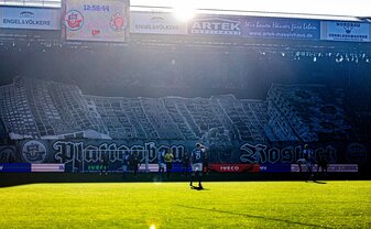 Hansa-Fans haben ein Banner mit Häusern aus Rostock-Lichtenhagen über die Tribüne gezogen. Hansa-Fans haben ein Banner mit Häusern aus Rostock-Lichtenhagen über die Tribüne gezogen.