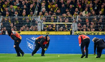 Stadionmitarbeiter sammeln Tennisbälle ein, die Fans auf das Spielfeld geworfen haben, um gegen Investoren in der DFL zu protestieren.