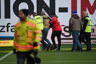 Ein Anhänger von Hansa Rostock wird von Sicherheitskräften vom Platz geführt. Ein Anhänger von Hansa Rostock wird von Sicherheitskräften vom Platz geführt.