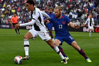 Deutschlands Jamal Musiala und der US-Amerikaner Tim Reamm liefern sich einen Zweikampf um den Ball. Deutschlands Jamal Musiala und der US-Amerikaner Tim Reamm liefern sich einen Zweikampf um den Ball.