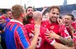 Die Spieler von Energie Cottbus bejubeln nach Schlusspfiff und Platzsturm den Aufstieg mit den Fans.