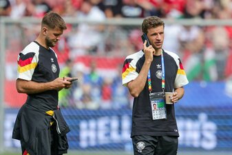 Deutschlands Thomas Müller (r) steht telefonierend mit einem Getränk auf dem Rasen, neben ihm Niclas Füllkrug. Deutschlands Thomas Müller (r) steht telefonierend mit einem Getränk auf dem Rasen, neben ihm Niclas Füllkrug.
