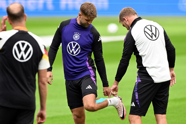 Niclas Füllkrug (M) nach seinem vergeblichen Härtetest beim Abschlusstraining im Gespräch mit Bundestrainer Julian Nagelsmann (r). 