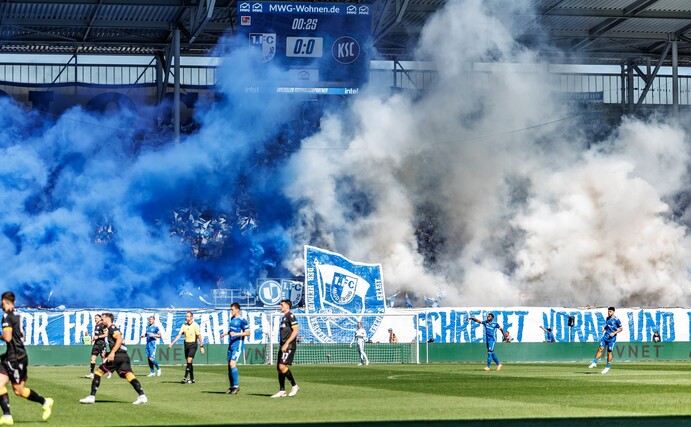 Die Magdeburger Fans zeigen ein fragwürdiges Banner und betonen dies mit Pyrotechnik.