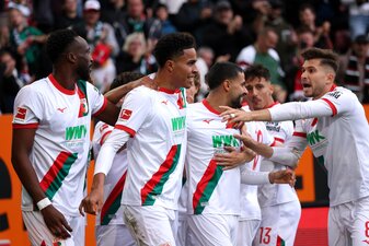 AUGSBURG, GERMANY - OCTOBER 04: Noahkai Banks of Augsburg celebrates scoring his team's first goal with teammates during the Bundesliga match between FC Augsburg and VfL Wolfsburg at WWK-Arena on Octo AUGSBURG, GERMANY - OCTOBER 04: Noahkai Banks of Augsburg celebrates scoring his team's first goal with teammates during the Bundesliga match between FC Augsburg and VfL Wolfsburg at WWK-Arena on Octo