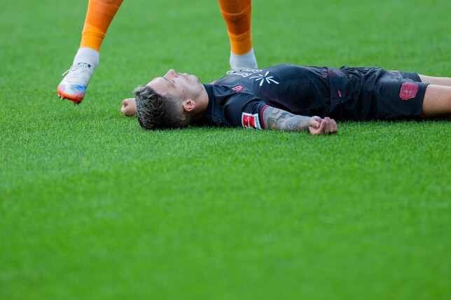 Bayer Leverkusens Kapitän Alejandro Grimaldo liegt nach einem Zusammenprall mit dem eigenen Mann benommen auf dem Boden. 