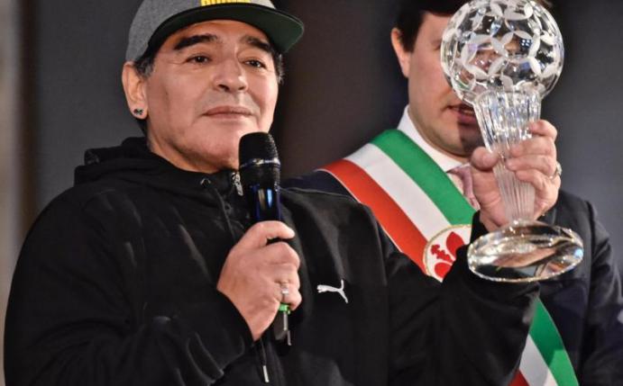 Die argentinische Fußballlegende Diego Maradona zeigt in Florenz seine Auszeichnung, die er im Zuge der Aufnahme in die Ruhmeshalle des italienischen Fu0balls erhalten hat. Foto: Maurizio Degl'innocenti