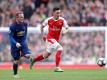 Arsenals Mesut Özil (r) in Aktion gegen Wayne Rooney von Manchester United. Foto: Adam Davy/PA Wire