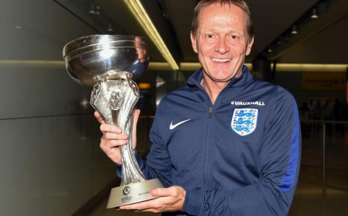 Keith Downing, der Trainer von Englands U19-Fußball-Nationalmannschaft zeigt den Pokal auf dem Flughafen Heathrow in London. Foto: Dan Law