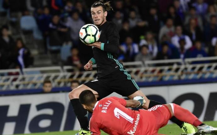 Madrids Gareth Bale (oben) spitzelt den Ball über San Sebastians Gerónimo Rulli zum 3:1 ins Tor. Foto: Alvaro Barrientos