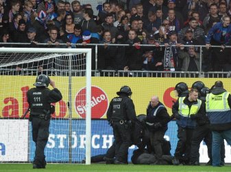 Polizisten und Ordner halten Kieler Randalierer auf dem Rasen fest. Foto: Axel Heimken