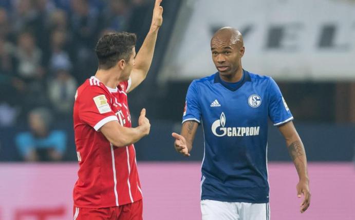 Bayerns Robert Lewandowski (l) diskutiert mit dem Schalker Naldo. Foto: Guido Kirchner