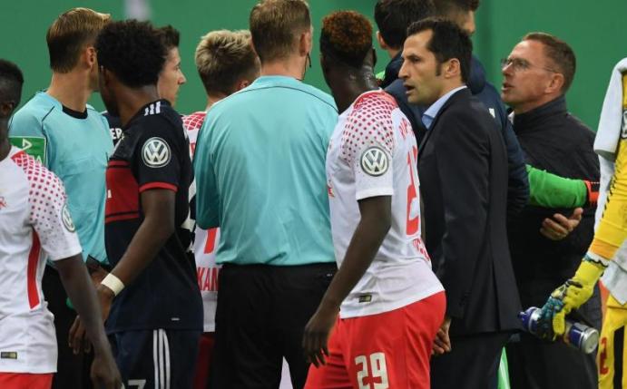 Leipzigs Sportdirektor Ralf Rangnick (r) wird in der Halbzeitpause von Mats Hummels (verdeckt) daran gehindert mit Schiedsrichter Zwayer zu diskutieren. Foto: Hendrik Schmidt