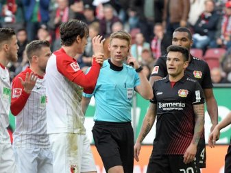 Im Mittelpunkt bei der Partie Augsburg gegen Leverkusen: Schiedsrichter Christian Dingert (M) beim Funkkontakt mit dem Videoschiedsrichter. Foto: Stefan Puchner