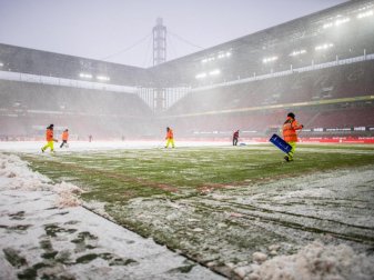 Ordner des 1. FC Köln räumen die Schneemassen vom Rasen. Foto: Guido Kirchner