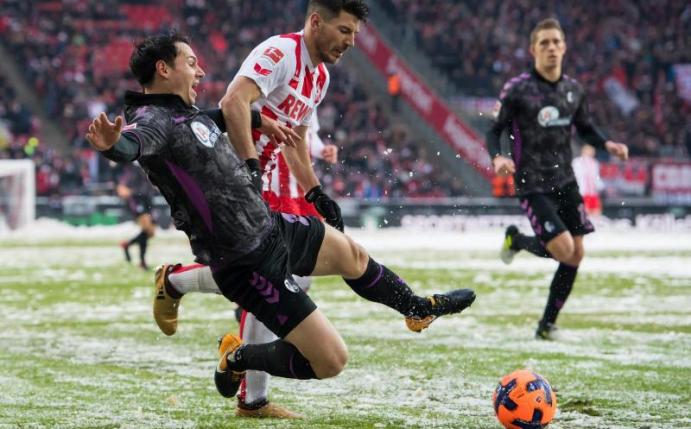 Der Freiburger Nicolas Höfler (l) grätscht gegen den Kölner Milos Jojic. Foto: Guido Kirchner