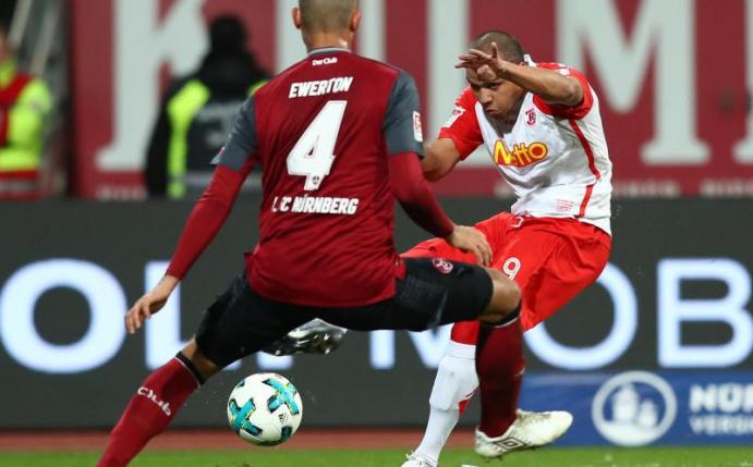 Nürnbergs Ewerton (l) blockt im Spiel gegen Jahn Regensburg einen Ball von Jann George. Foto: Daniel Karmann