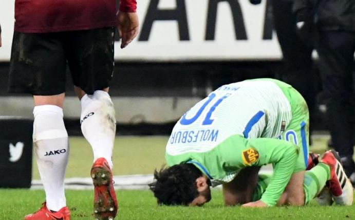 Wolfsburgs Yunus Malli küsst den Rasen im Stadion von Hannover 96: «Ich kann mich nicht erinnern, je auf einem so schlechten Platz gespielt zu haben», sagte Torschütze. Foto: Peter Steffen