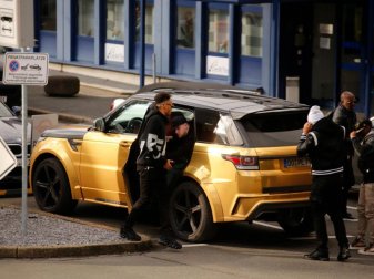 Pierre-Emerick Aubameyang (l) kommt mit einem goldfarbenen Land Rover zum Dortmunder Flughafen. Foto: Guido Kirchner Pierre-Emerick Aubameyang (l) kommt mit einem goldfarbenen Land Rover zum Dortmunder Flughafen. Foto: Guido Kirchner