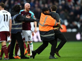 Ein Fan, der den Platz gestürmt hatte, wird von einem Sicherheitsmitarbeiter festgehalten, während James Collins (M) von West Ham ihn anbrüllt. Foto: Daniel Hambury/PA Wire