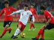 Polens Starspieler Robert Lewandowski (M) setzt sich gegen zwei Südkoreaner durch. Foto: Andrzej Grygiel/PAP