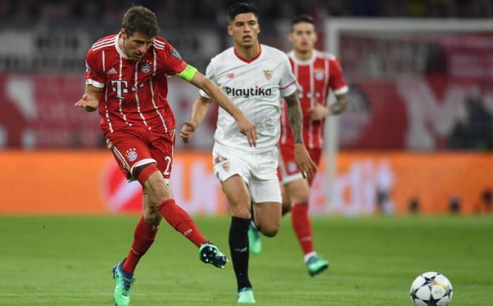 Bayern-Kapitän Thomas Müller (l) zieht ab, Sevillas Carlos Joaquin Correa hat das Nachsehen. Foto: Sven Hoppe