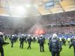 Feuerwerkskörper brennen vor dem Abpfiff auf der Tribüne, während Polizisten auf dem Spielfeld stehen. Foto: Daniel Bockwoldt